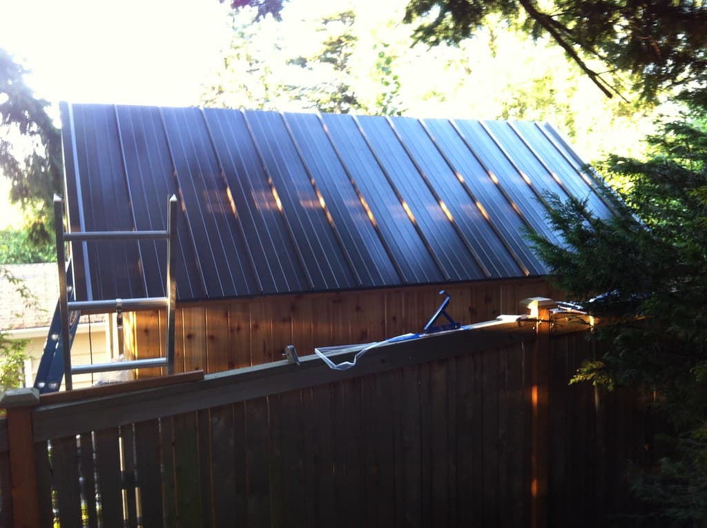 A ladder against a dark corrugated metal roof during restoration work